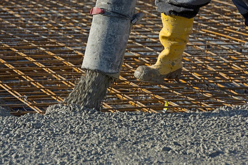 Construction worker pours concrete onto reinforcing steel using a concrete pump