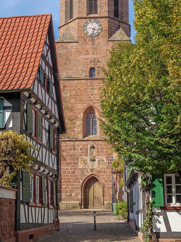 View of church with clock and half-timbered houses in a small cobbled village street, Kandel, Palatinate, Germany, Europe