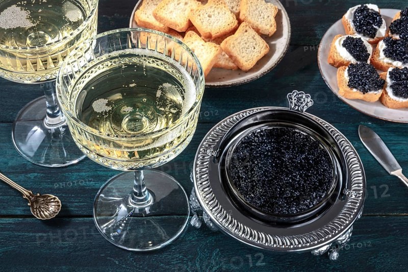 Caviar and champagne, vintage style, with bread and toasts on a dark blue wooden background