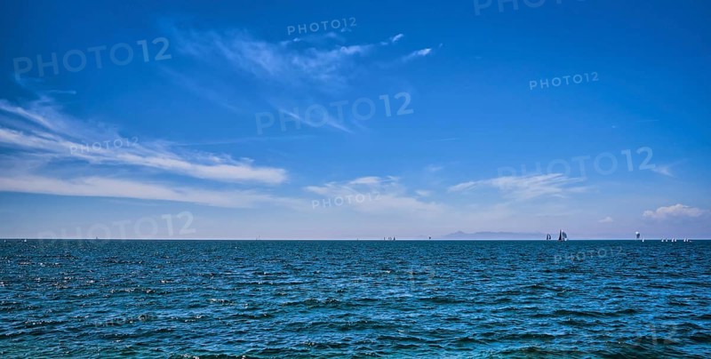 Panoramic beautiful seascape on a bright summer day with few sailing boats afar, great sky with dynamic clouds. Peaceful vacation, meditative, relaxing view. Weekend by sea, beach, contemplation
