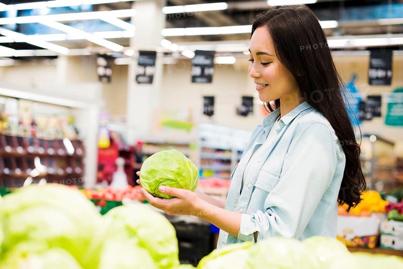 Smiling asian woman choosing cabbage market