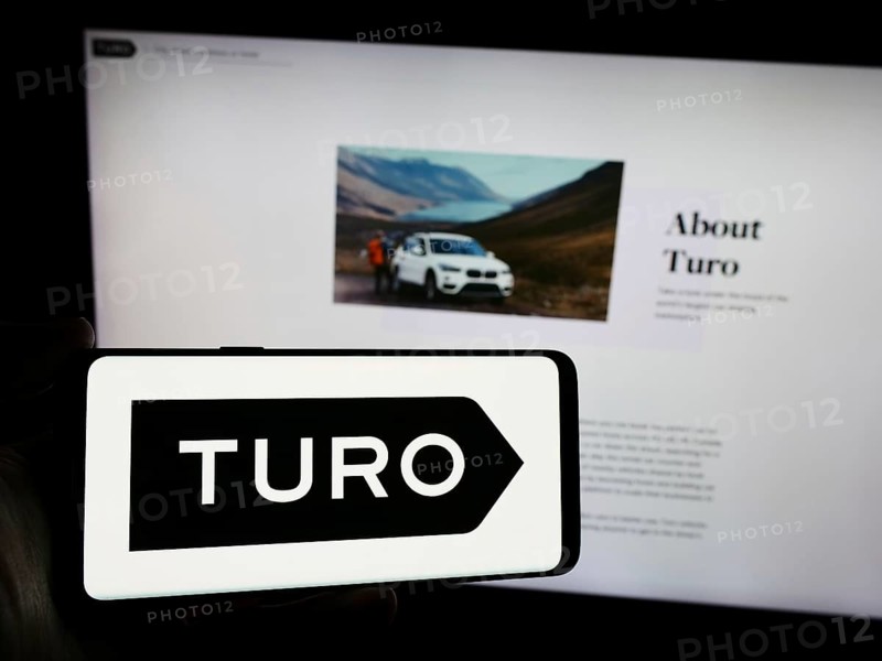 Stuttgart, Germany, 03-18-2024: Person holding smartphone with logo of US peer-to-peer carsharing company Turo Inc. in front of website. Focus on phone display, Europe