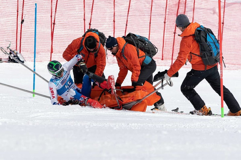 KAMCHATKA PENINSULA, RUSSIA, MAR 28, 2019: Rescuers Kamchatka Rescue Squad on alpine ski evacuate injured skier sportsman from mountain on tactical rescue stretchers during competition alpine skiing
