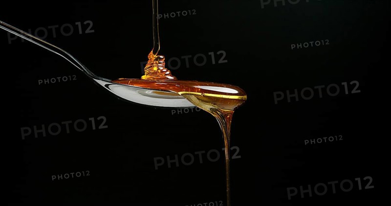Honey Flowing against Black Background