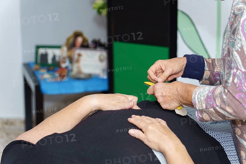 A therapist places magnets on a patient's body during a biomagnetism session
