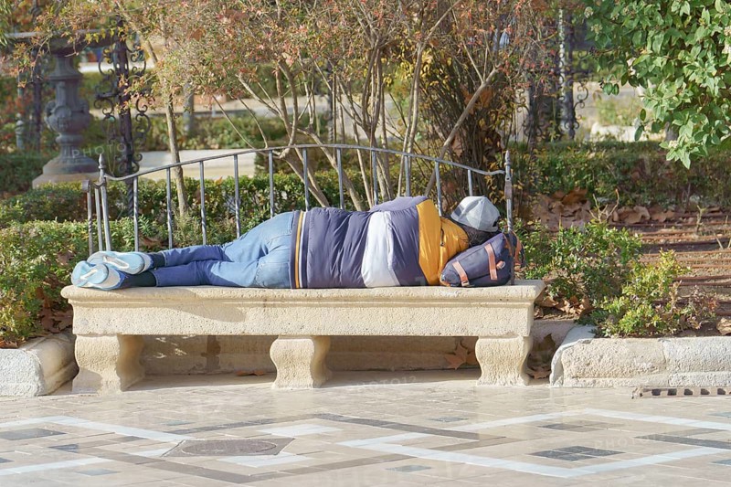 Homeless man sleeping on a park bench