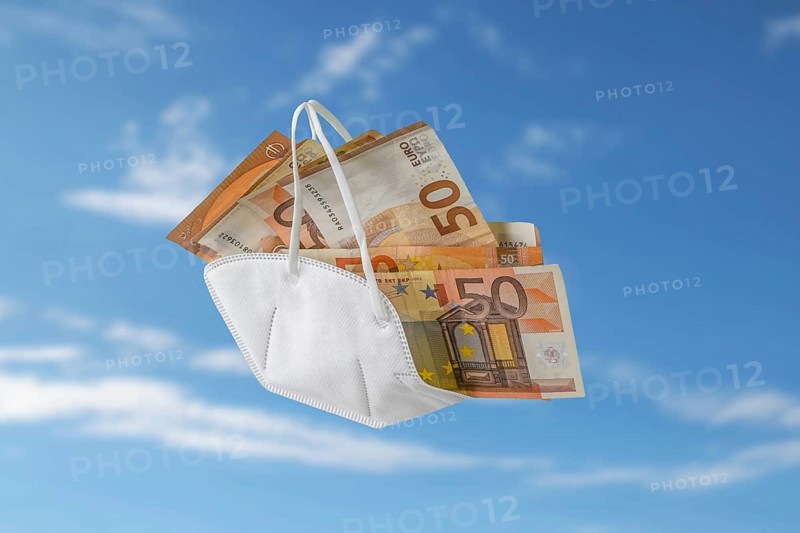 Medical ffp2 face mask against covid-19 filled like a bag with euro banknotes, concept for enrichment by corruption or rising costs in health care, blue sky with blurry clouds, copy space