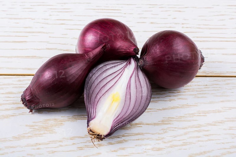 Red onion bulb cut in half on a certain background