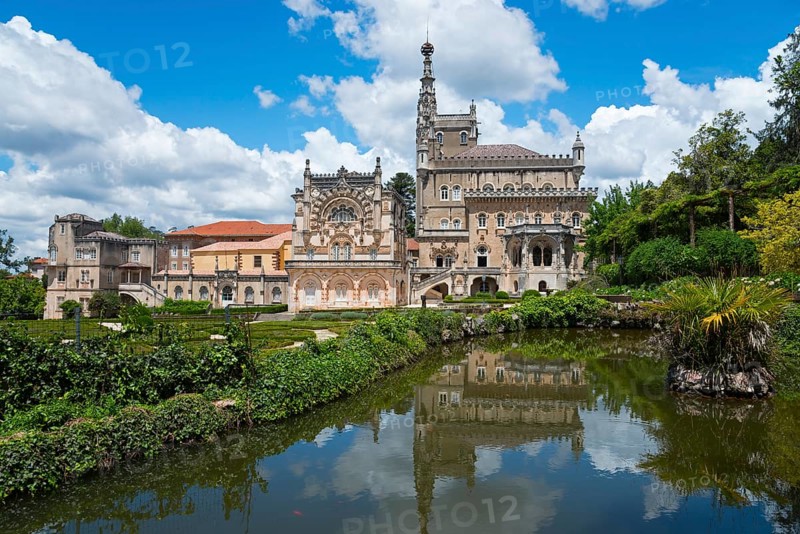 Historisches Schloss mit reflektiertem Bild im See, umgeben von Bäumen und bewölktem Himmel, Palácio Hotel do Buçaco, Mata Nacional do Buçaco, National-Wald von Bussaco, Bucaco, Mealhada, Beira Litoral, Portugal, Europe