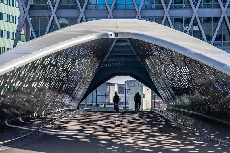 The Parkbruk, cycle and pedestrian bridge in the city centre of Antwerp, crosses a multi-lane city centre road, with tram lines, and thus connects two lively city districts Kop Spoor Noord and Eilandje, light effects by the sun, on the roadway, Belgium, Europe
