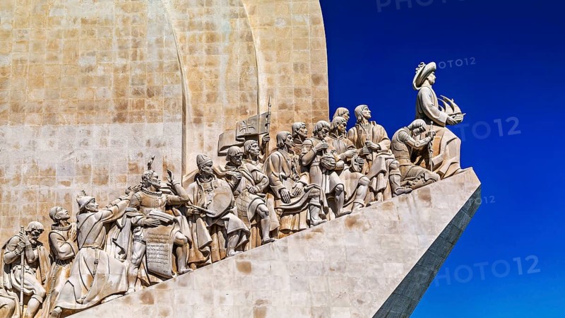 Monumentale Statuengruppe unter klarblauem Himmel, die historische Figuren der portugiesischen Geschichte darstellt, Lisbon