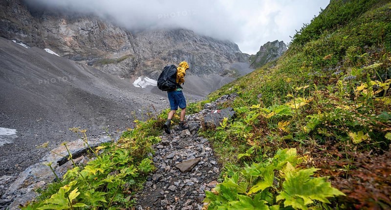 Mountaineer hiking in the mountains with yellow jacket, hiking trail to Valentintörl, cloudy mountain peaks, Carnic Alps, Carnic High Trail, Carinthia, Austria, Europe