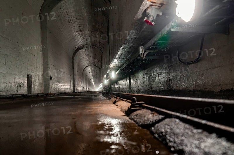 Deep tunnel with wet concrete walls and light at the end, industrial ambience, Rappbodetalsperre, Harz, Germany, Europe
