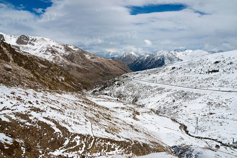Winterliche Landschaft in den schneebedeckten Bergen von Andorra mit einer Straße und Wolken am Himmel, nördlich von El Pas de la Casa, Pyrénées-Orientales, Encamp, Fürstentum Andorra, Pyrenäen
