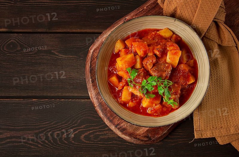 Stew with potatoes, in tomato sauce, with spices and herbs, close-up, no people, on a black background