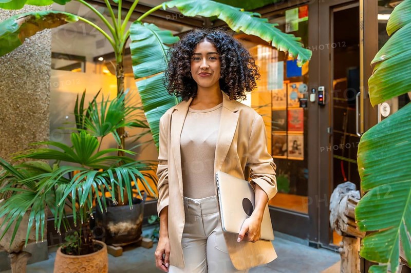 Three quarter length portrait of a beauty young businesswoman standing carrying a laptop next to coworking office