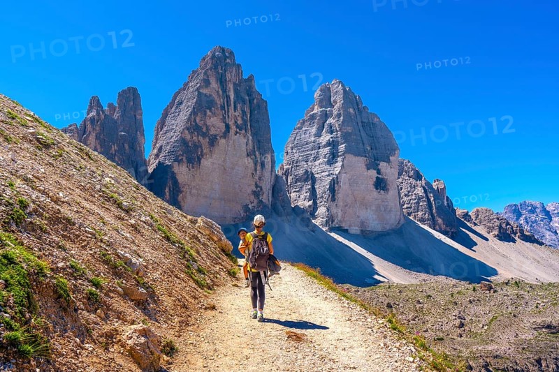 Tourists walking on a mountain path near tre cime di lavaredo, dolomites, a famous landmark in italy