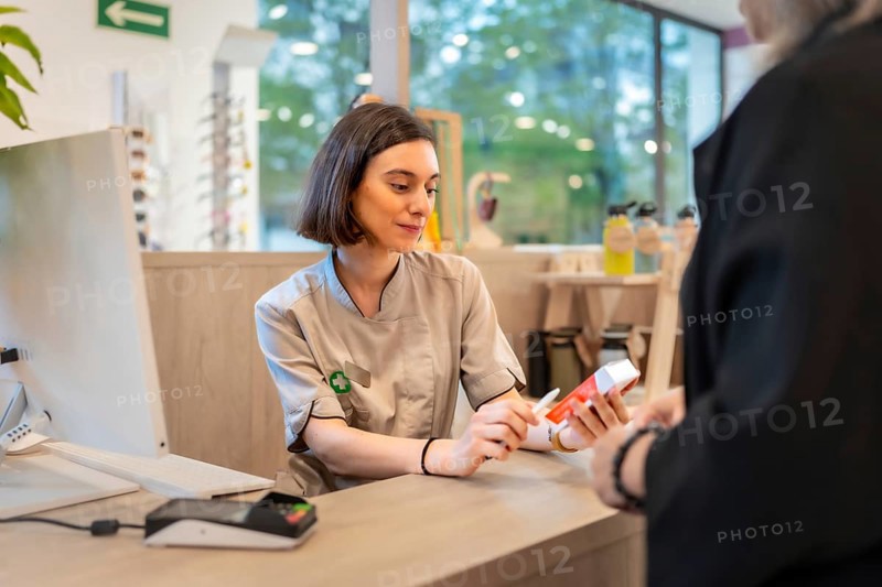 Young beauty female pharmacist attending a client in the store