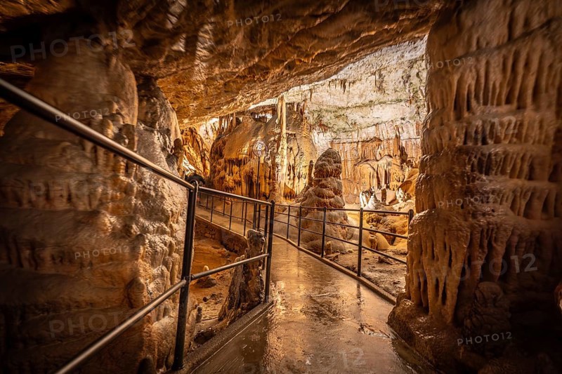 Tourists enjoying a guided tour walking on the footpath inside the famous postojna cave, a natural wonder in slovenia