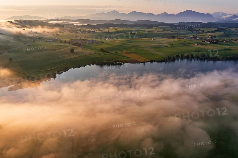 Aerial view of a lake in front of mountains in the morning light, fog, autumn, Riegsee, view of Benediktenwand and Jochberg, Alpine foothills, Upper Bavaria, Bavaria, Germany, Europe