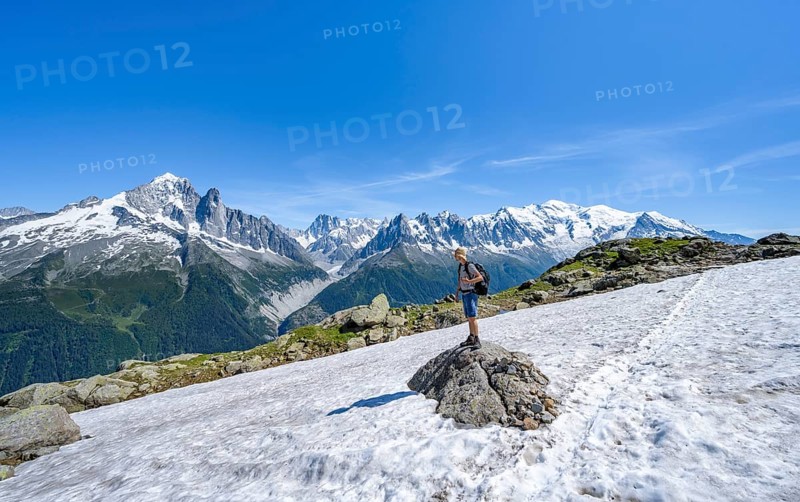 Mountaineer on a hiking trail in front of a mountain landscape, view of mountain peaks Aiguille Verte, Grandes Jorasses and Mont Blanc of the Mont Blanc massif, Aiguilles Rouges, Chamonix-Mont-Blanc, Haute-Savoie, France, Europe