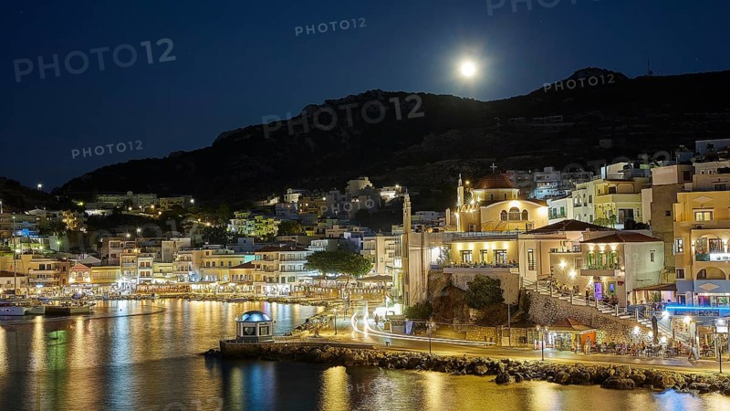 Illuminated coastal town at night with moon in the sky and water in the foreground, Rising full moon, Pigadia, town and harbour, Pigadia Bay, main town, Karpathos, Dodecanese, Greek Islands, Greece, Europe