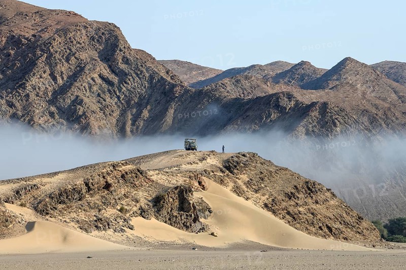 Safari vehicle on a hill in the Hoanib dry river, coastal fog, Kaokoveld, Kunene Region, Namibia, Africa