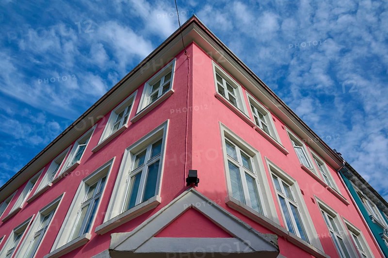 Historic building with pink facade and white window frames under a blue sky with light clouds, Bergen, Vestland, Norway, Europe