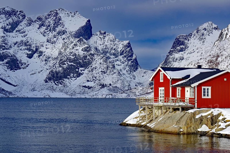 Red house by the fjord in front of snow-covered mountains in a wintry landscape, Scandinavian style with wooden structure, Rorbuer, holiday, Hamnöy, Lofoten, Nordland, Norway, Europe