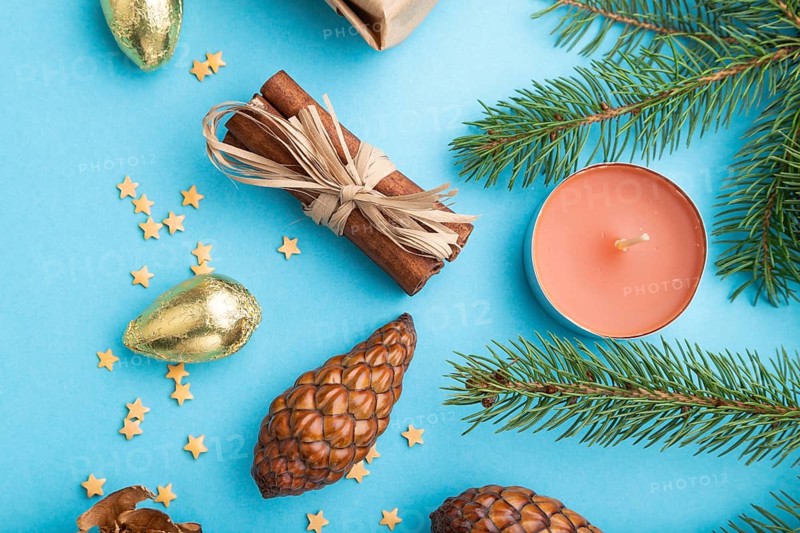 Christmas or New Year composition. Decorations, box, cinnamon, cones, fir and spruce branches, on a blue paper background. Top view, close up, flat lay