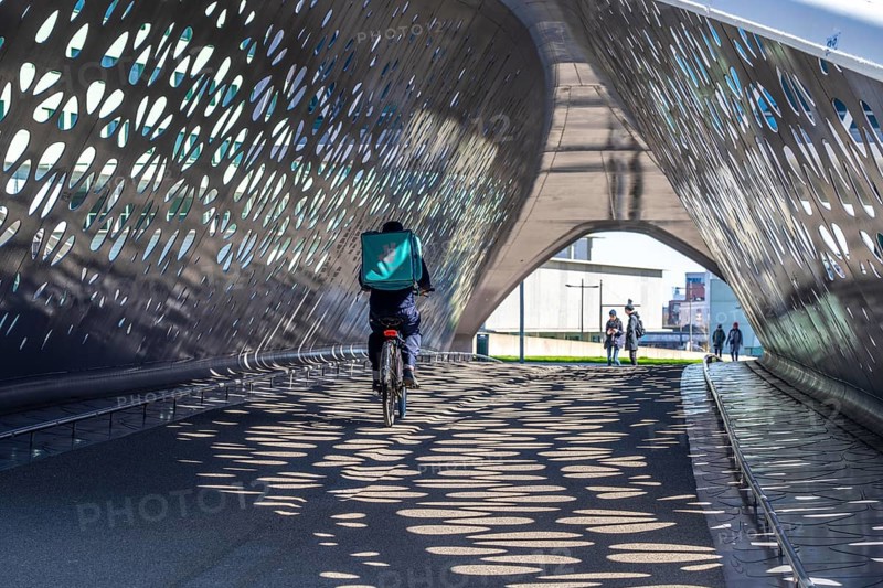 Light effects from the sun in the Parkbruk, a cycle and pedestrian bridge in the city centre of Antwerp, spanning a multi-lane city centre road with tram lines, and thus connecting two lively city districts Kop Spoor Noord and Eilandje, Belgium, without any crossings, Europe