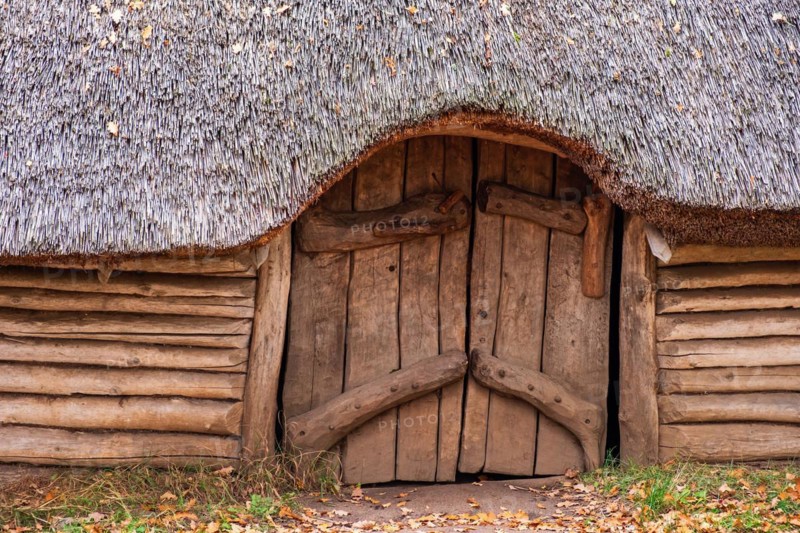 Entrance to a longhouse built of tree logs and a detached roof of reeds