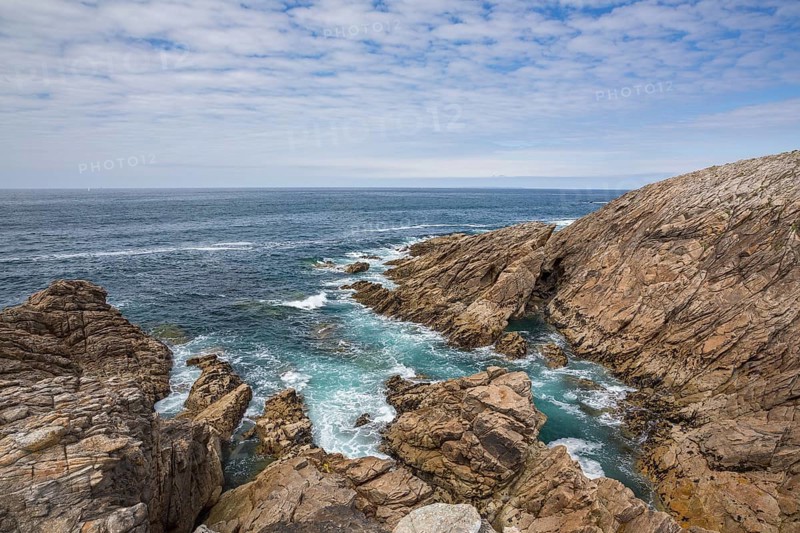 Rocky west coast of the Quiberon peninsula in Brittany, France, with a partly cloudy sky. Crashing waves and rocks, Europe
