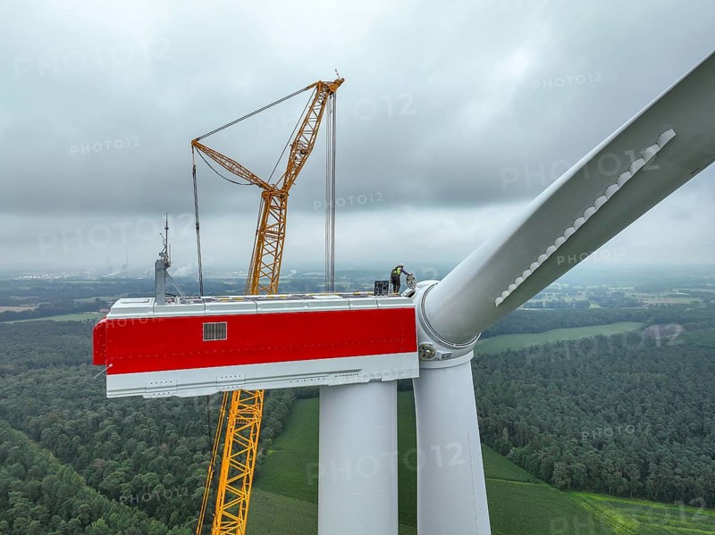 Dorsten, North Rhine-Westphalia, Germany, construction of a wind turbine. A large mobile crane lifts a rotor blade to the nacelle on the tower. Here, the blade is mounted directly on the motor hub. Große Heide wind farm, Europe