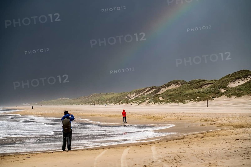 Walkers on the beach, dark storm clouds, choppy sea, autumn on the North Sea in North Holland, between the towns of Egmond aan Zee and Bergen aan Zee, Netherlands
