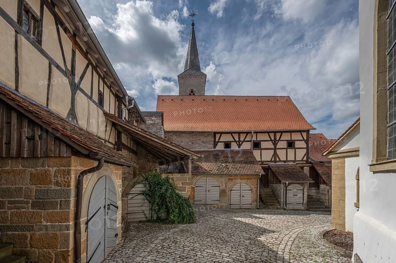 Former so-called Kirchgaden, barns in the historic fortified church, behind the tower of the church of St John the Baptist, Hüttenheim, Lower Franconia, Bavaria, Germany, Europe