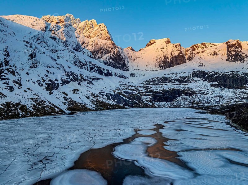 Aerial view of icy lake in front of steep mountains, winter, sunrise, Storvatnet, Flakstadoya, Lofoten, Norway, Europe