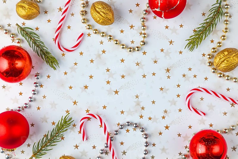 Frame made of Christmas decorations, fir branches, baubles, nuts on a white background with golden stars, copy room