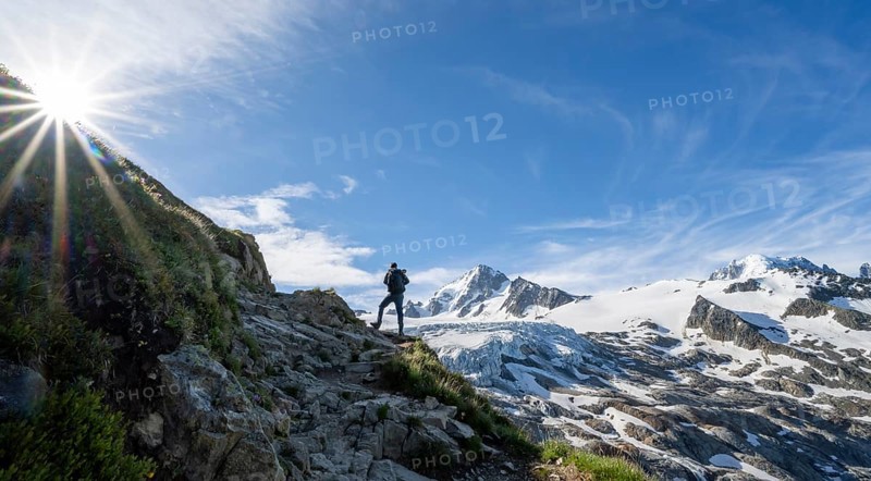 Mountaineer in front of high alpine mountain landscape with sun star, summit of Aiguille de Chardonnet and Glacier du Tour, glacier and mountain peaks, Chamonix, Haute-Savoie, France, Europe