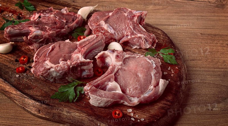 Raw calf meat, meat on the bone, meat for barbecue, cutting board, with spices and herbs, top view