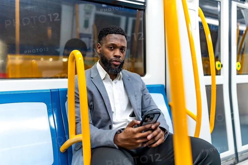 Young businessman sitting on a subway train, using a smartphone during his daily commute, staying connected in the urban environment