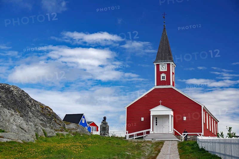 Red church with white entrance and tower, sculpture next door under a blue sky, Church of the Saviour, old town of the capital of Greenland, Nuuk, Greenland, Denmark, North America