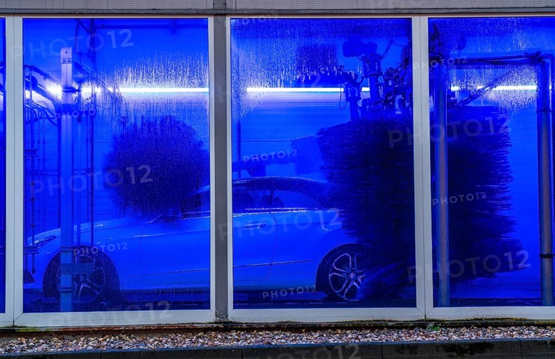 Car in an automatic car wash, car wash tunnel, cleaning foam is sprayed on, rotating brushes clean the vehicle