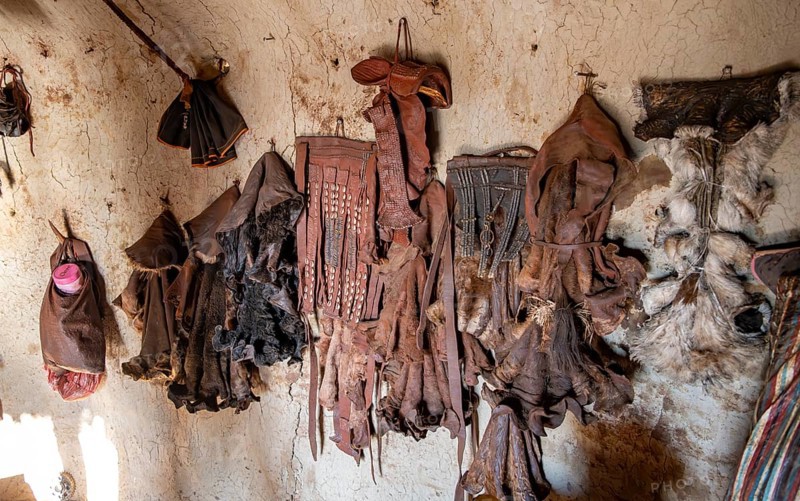 Various traditional leather aprons hanging on the wall, interior of a mud hut of the first woman in a Himba village, near Opuwo, Kaokoveld, Kunene, Namibia, Africa