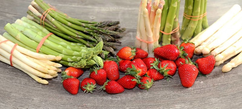 Green asparagus, white asparagus and fresh strawberries decorated on a rustic wooden table
