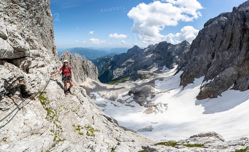 Mountaineer with helmet in a secured via ferrata, Zugspitz via ferrata, ascent to the Zugspitze, view of mountain basin with snowfield of the Höllentalferner and Höllental, Wetterstein range, Bavaria, Germany, Europe