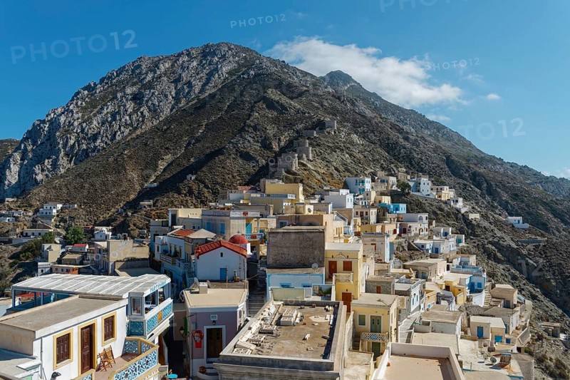Colourful houses of the picturesque village of Olymbos spread out on a mountainside under a clear blue sky, Olymbos, Karpathos, Greece, Europe