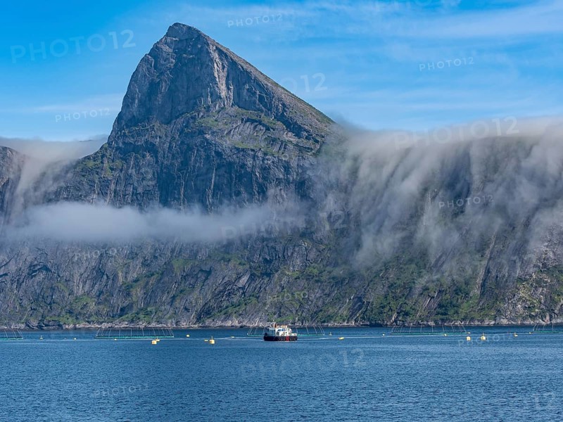 Salmon farm, aquaculture in the Mefjord on Senja island, in the background the peak of famous Segla mountain, Norway, Europe
