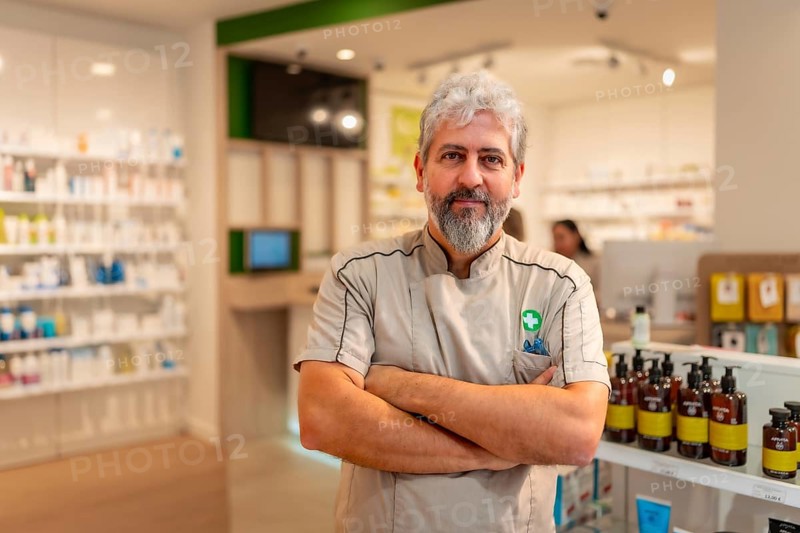 Proud mature man pharmacist standing with arms crossed in the store