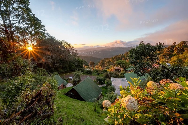 Cabins of a lodge in the cloud forest, in the evening light, Paraiso Quetzal Lodge, view over mountain landscape, sun star, San José province, Costa Rica, Central America